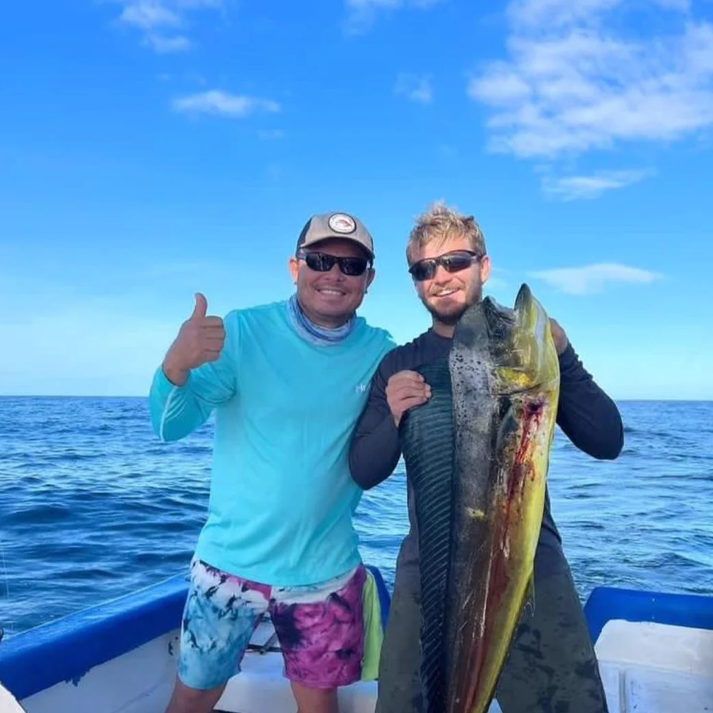 Two anglers with a dorado, thumbs up, blue sky behind them