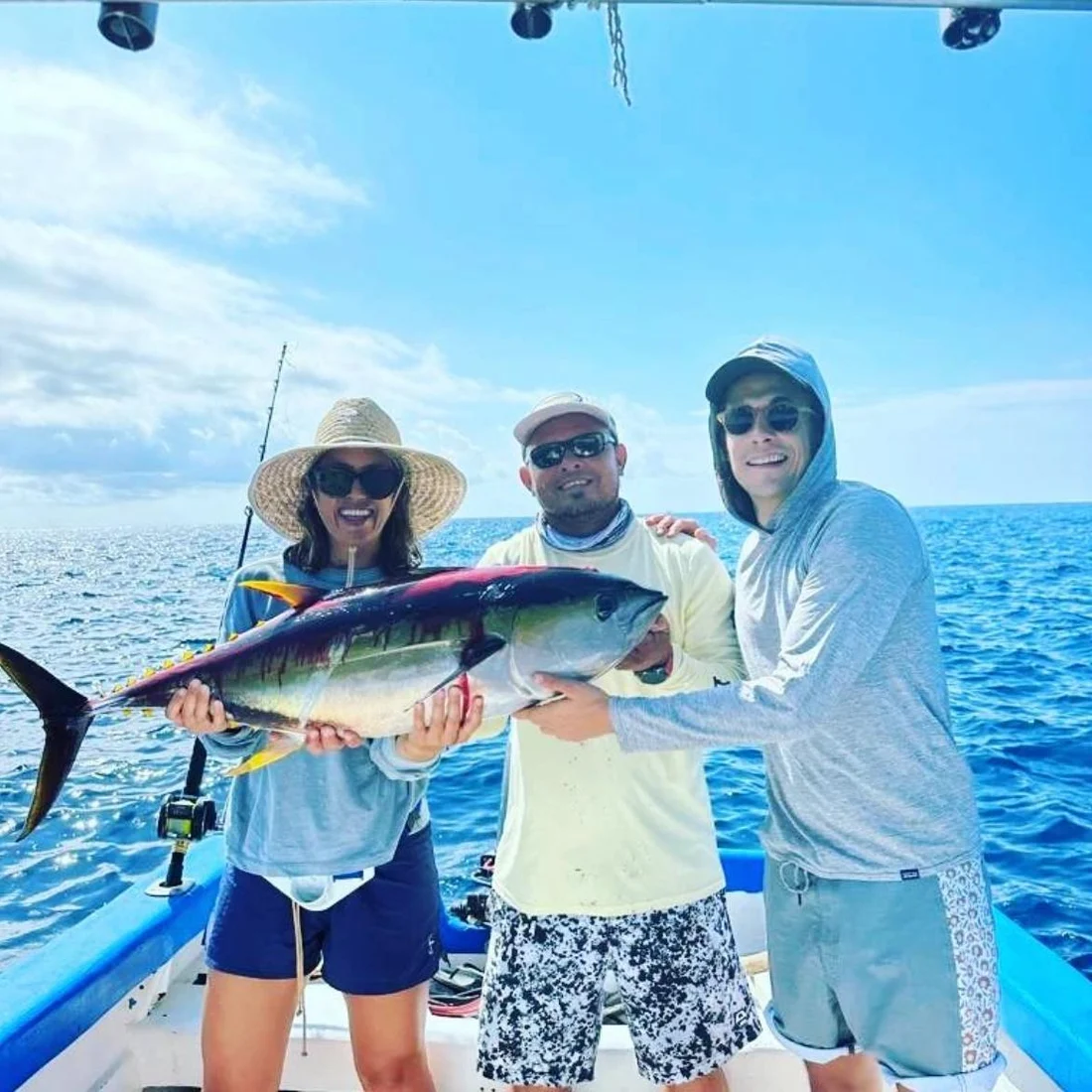 Three guests and the mate holding a yellowfin tuna between them