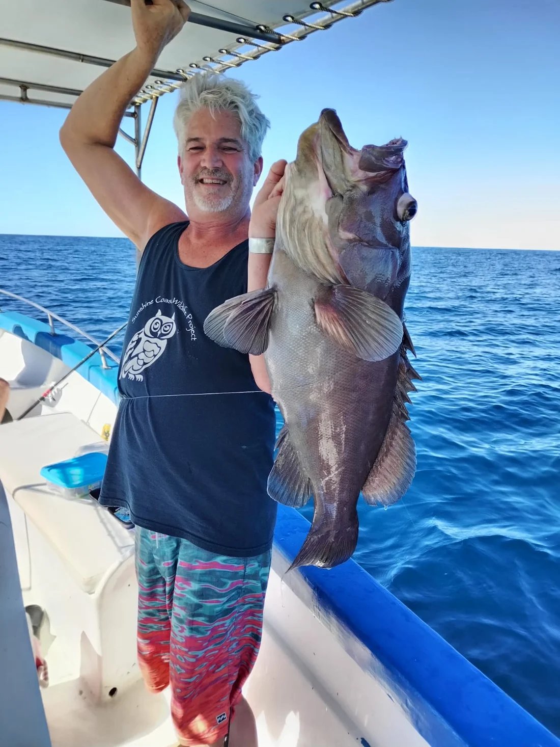 A guest on the bow holding a grouper caught off the rocks
